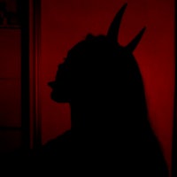 a silhouette of a woman with devil horns in front of a red door